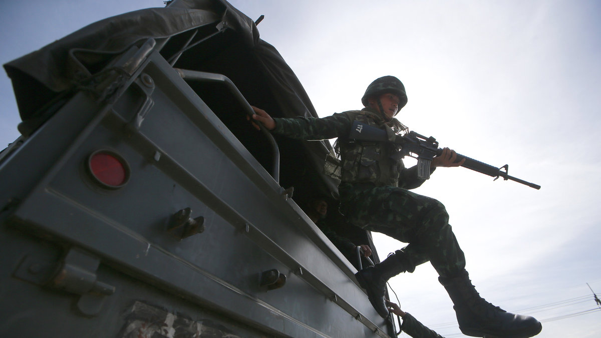 En soldat hoppar ut ur en lastbil i Bangkok, där militären tagit över säkerhetsläget. 