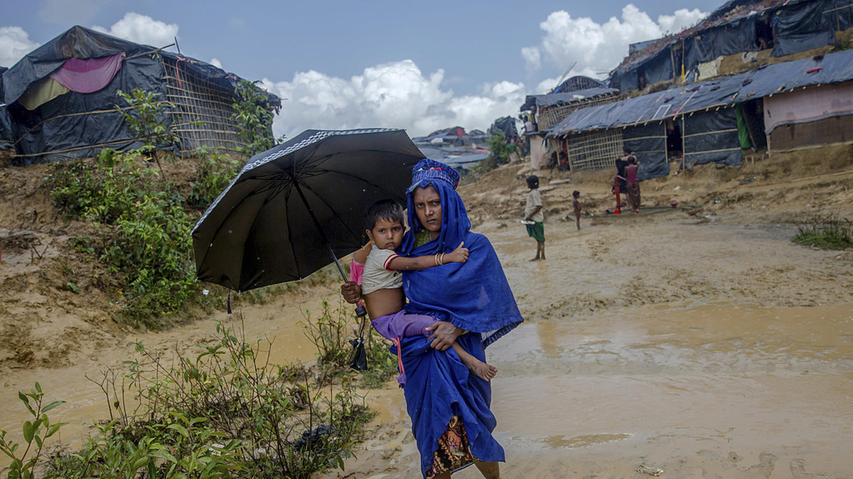 En Rohingyakvinna promenerar tillbaka mot sitt lägret Taiy Khali i Bangladesh efter att ha besökt en klinik med sin sjuka dotter, torsdag 21 september.

