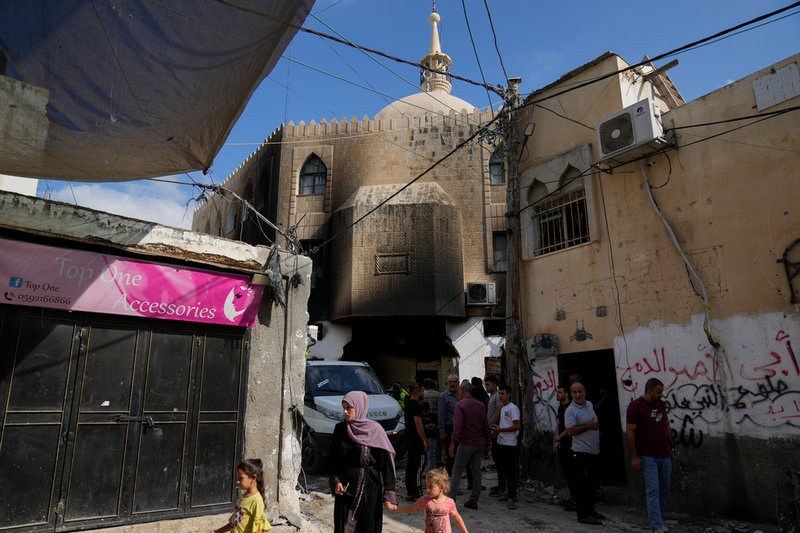 Palestinier utanför en moské som delvis förstörts under en israelisk räd mot al-Fara på Västbanken.