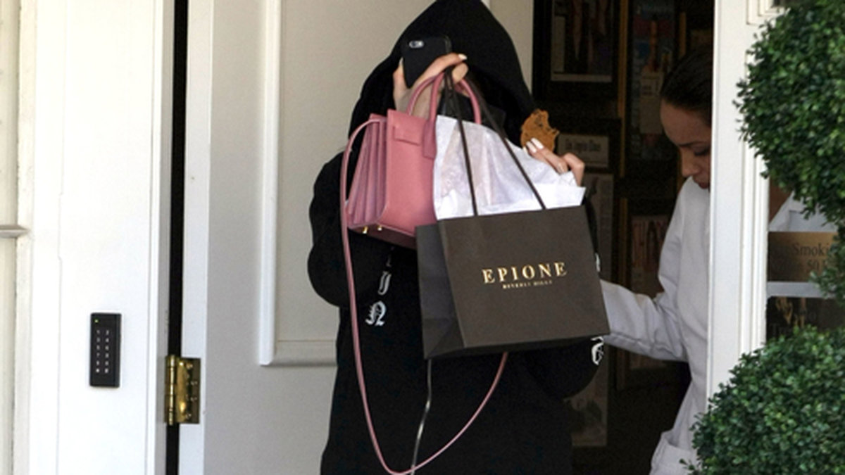 Kylie Jenner gömmer sig bakom väskor när hon lämnar en skönhetssalong.