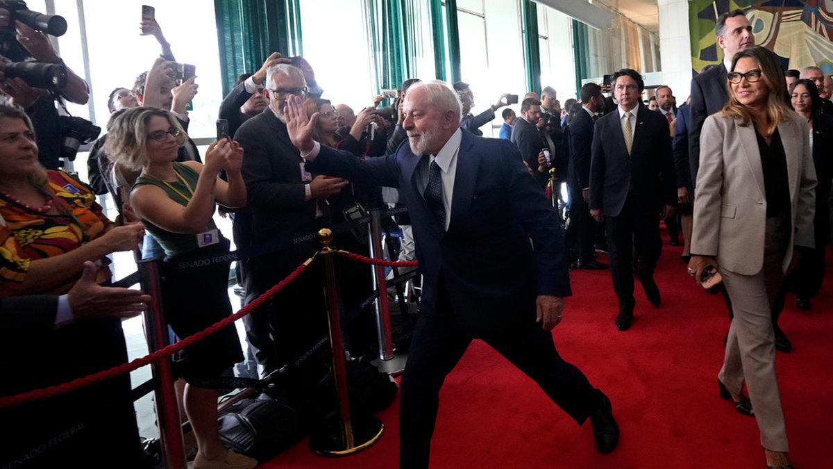 Brasiliens president Luiz Inácio Lula da Silva hälsar på journalister när han besöker kongressen, som utsattes för ett kuppförsök för ett år sedan.