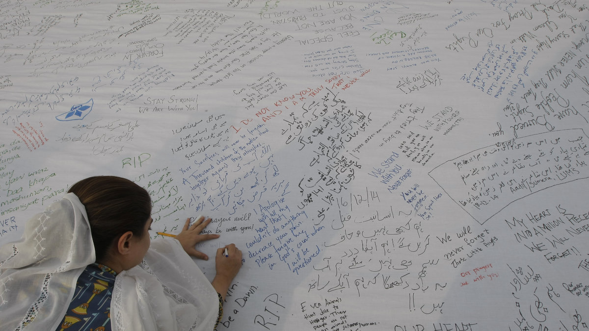 En pakistansk flicka skriver ett meddelande på en vägg tillägnat offren i skolmassakern. 