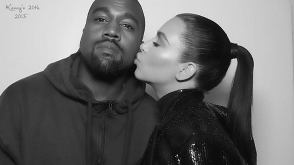 Kim Kardashian planterar en puss på Kanyes kind.