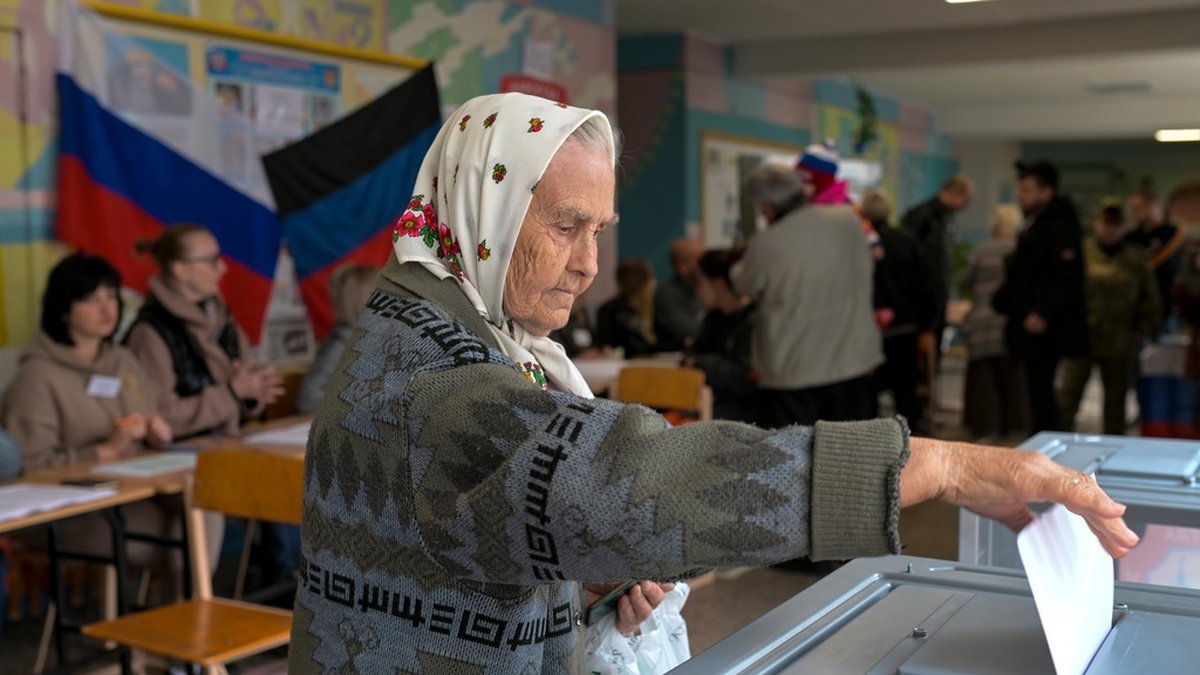 En kvinna röstar i en vallokal med den ryska flaggan på väggen, i staden Donetsk.