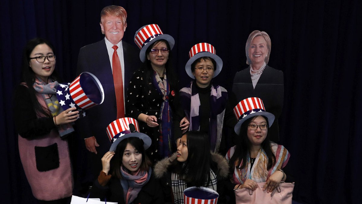 Kvinnor poserar tillsammans med pappfigurer föreställande Donald Trump och Hillary Clinton under valvakan i Peking, Kina. 