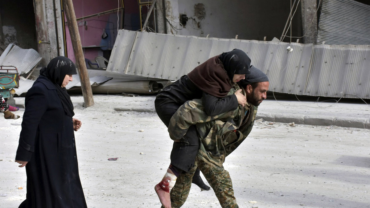 Här får en skadad civil kvinna hjälp av en soldat.