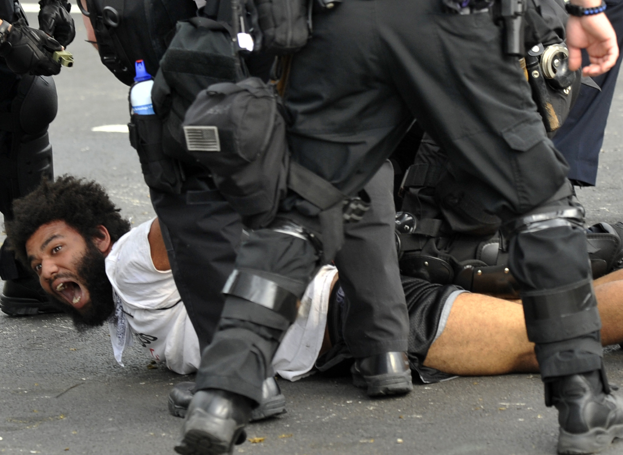 En demonstrant tvingas ner på marken av polis. 
