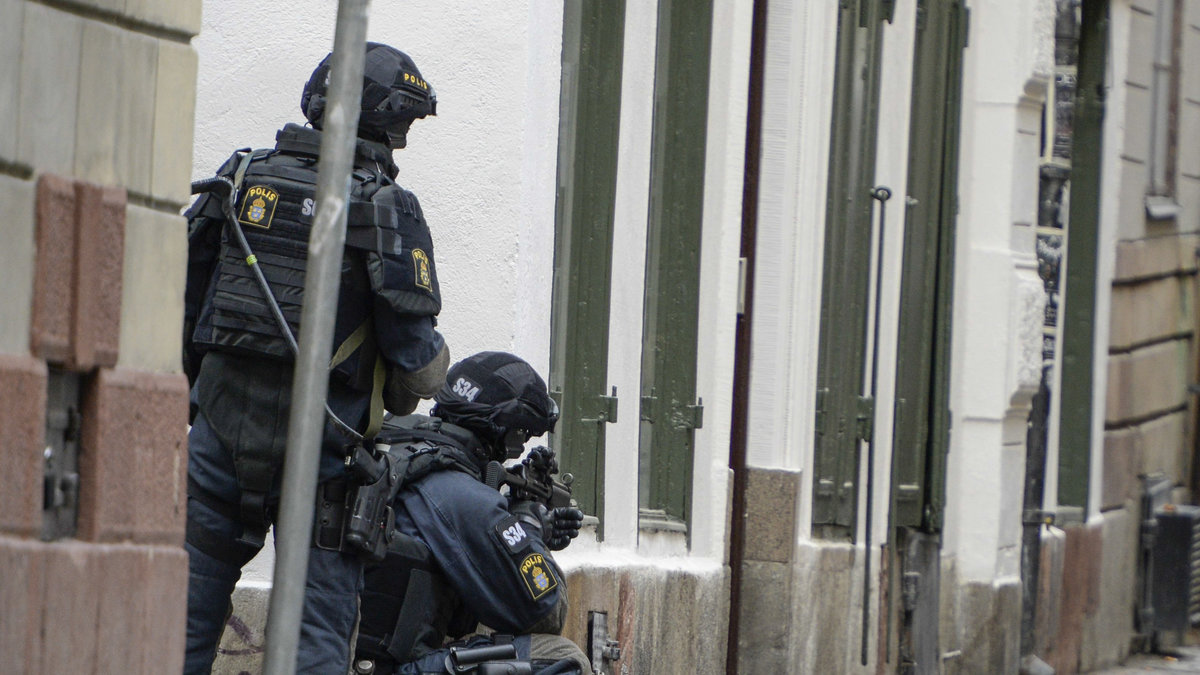 Beväpnad polis i gathörnen mot Stora Nygatan.