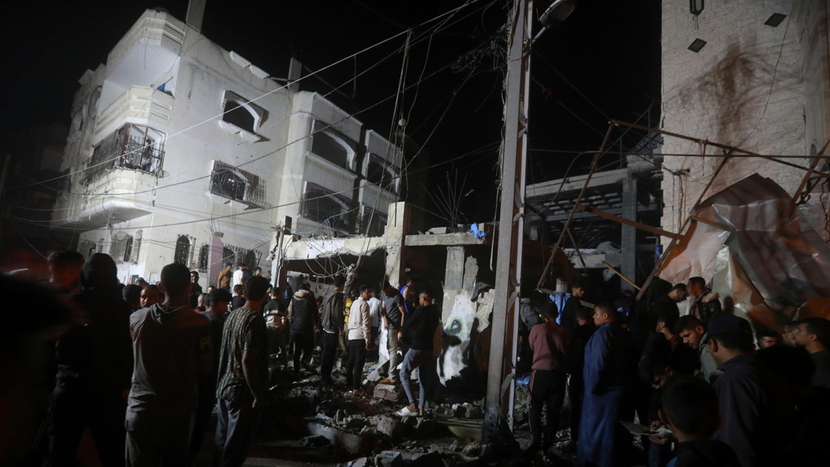 Palestinier vid en förstörd byggnad efter en israelisk attack mot ett flyktingläger i Rafah i Gaza. Arkivbild.