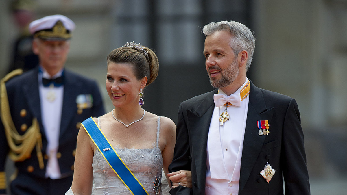 Prinsessan Märtha Louise bar en silvergrå klänning med broderade detaljer. Ari Behn står vid hennes sida.