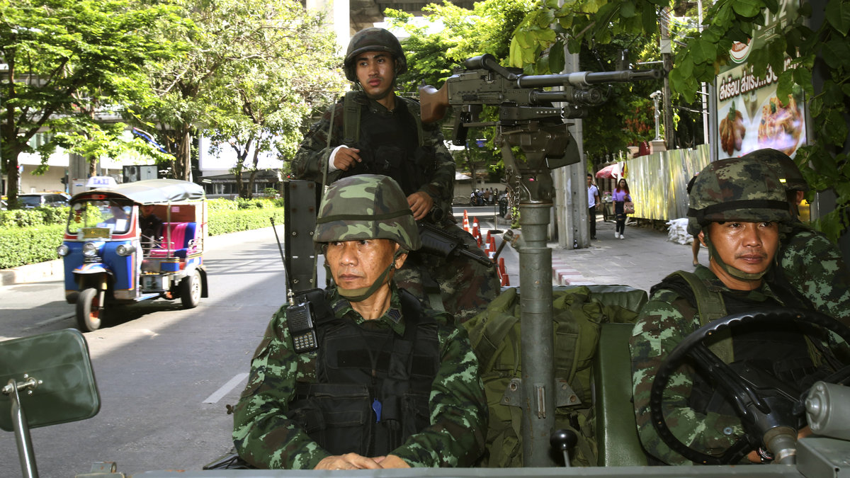 A tuk tuk-förare passerar militär som är stationerad utanför polisens högkvarter. 