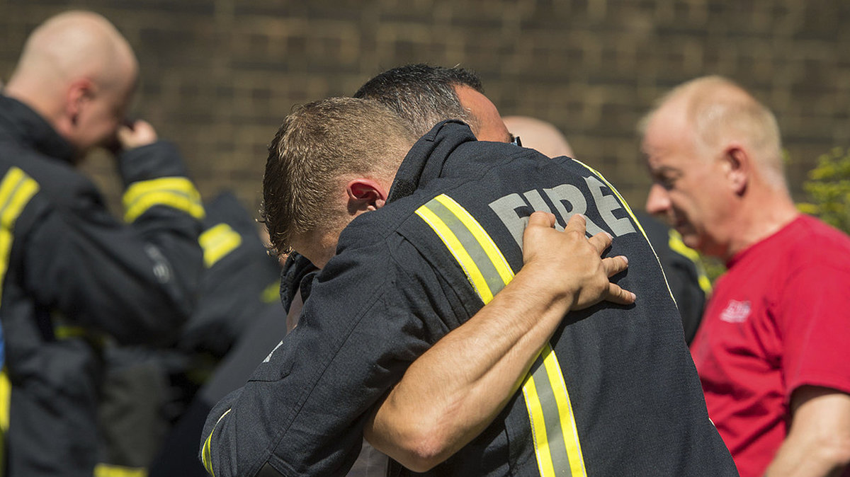Det är viktigt att stötta varandra i svåra stunder - här kramas en brandman med en av de anhöriga.
