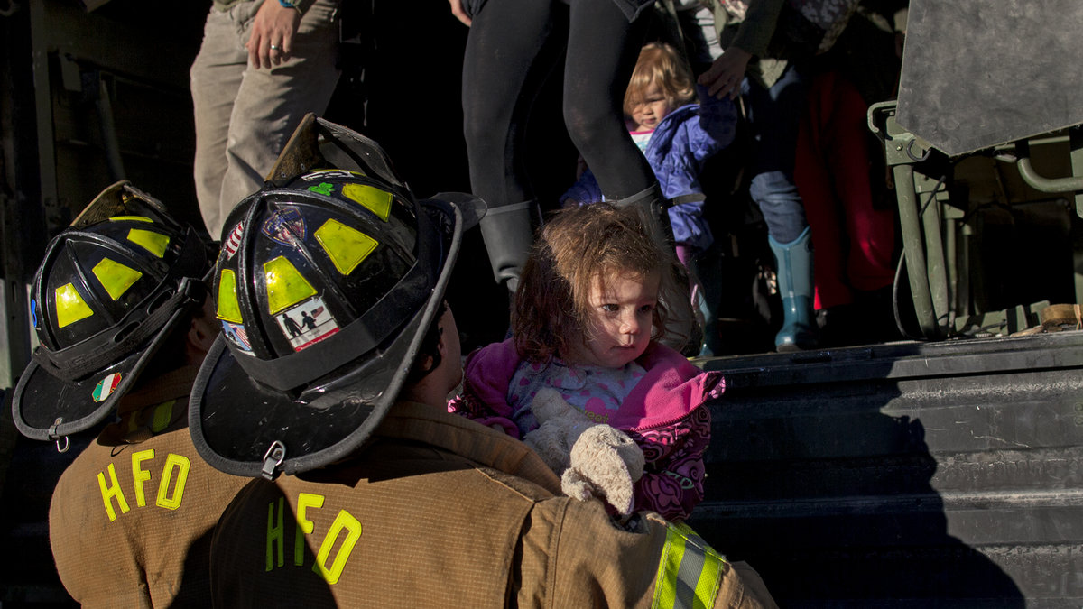 En flicka räddas av brandmän när stormen nu blåst över.