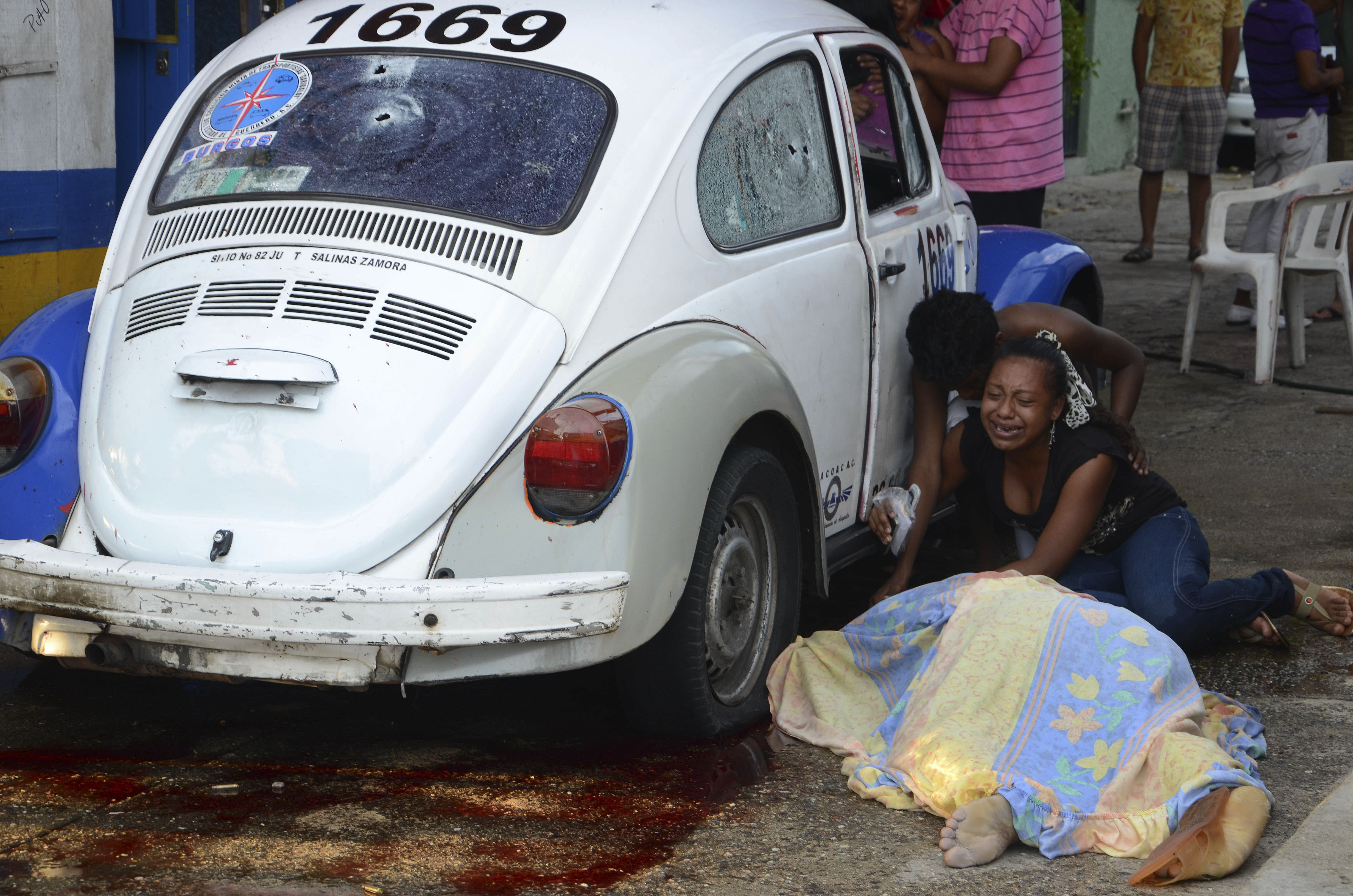Anhöriga sörjer efter att beväpnade män börjat skjuta mot en taxi och dödat föraren och passageraren.