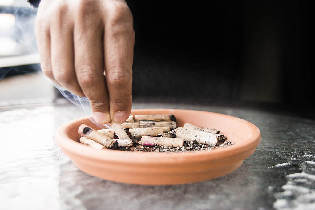 Person som fimpar cigarett i askkopp Person som fimpar cigarett i askkopp