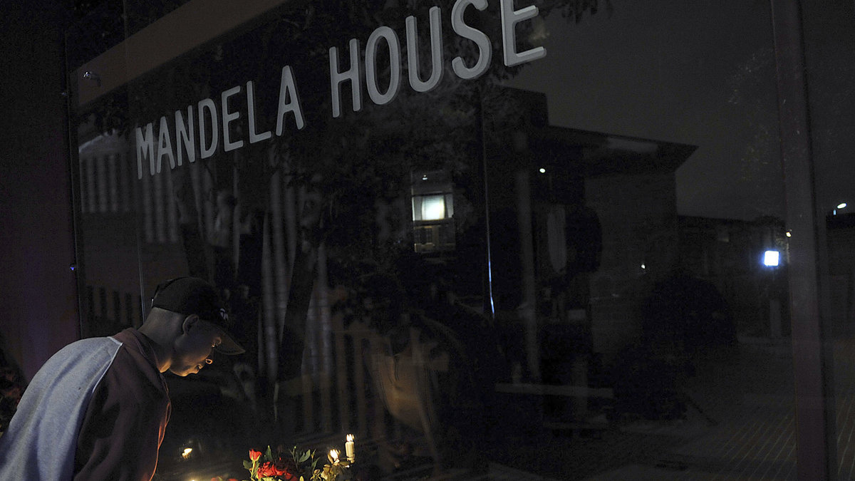 En man tänder ett ljus utanför Mandela House, hans tidigare hem, i Soweto.