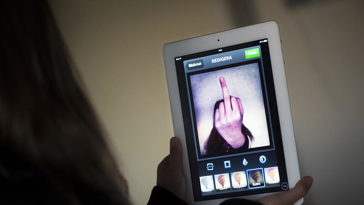 Bild på person som håller upp en ipad med en bild på en fuck you-finger.