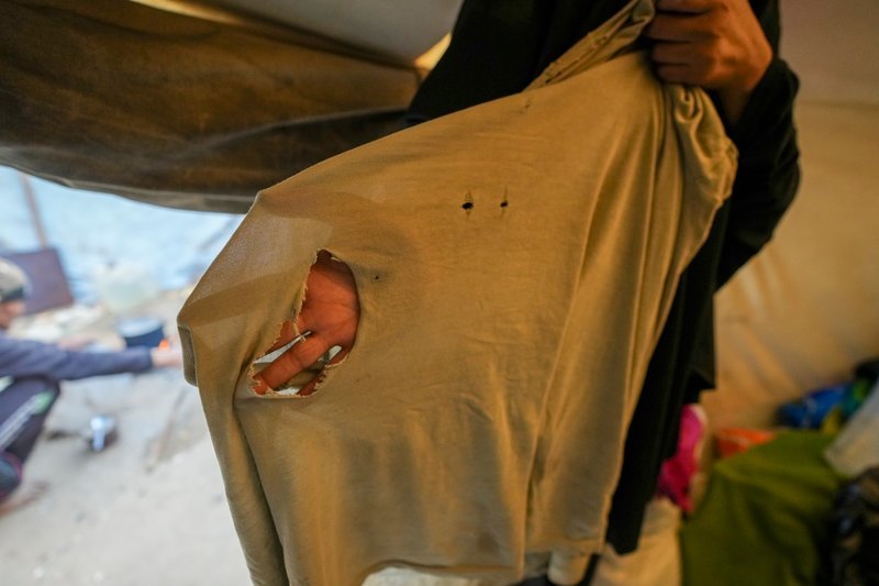 En kvinna som bor i Dayr al-Balah visar ett trasigt klädesplagg, som hon ska riva sönder till mensskydd.