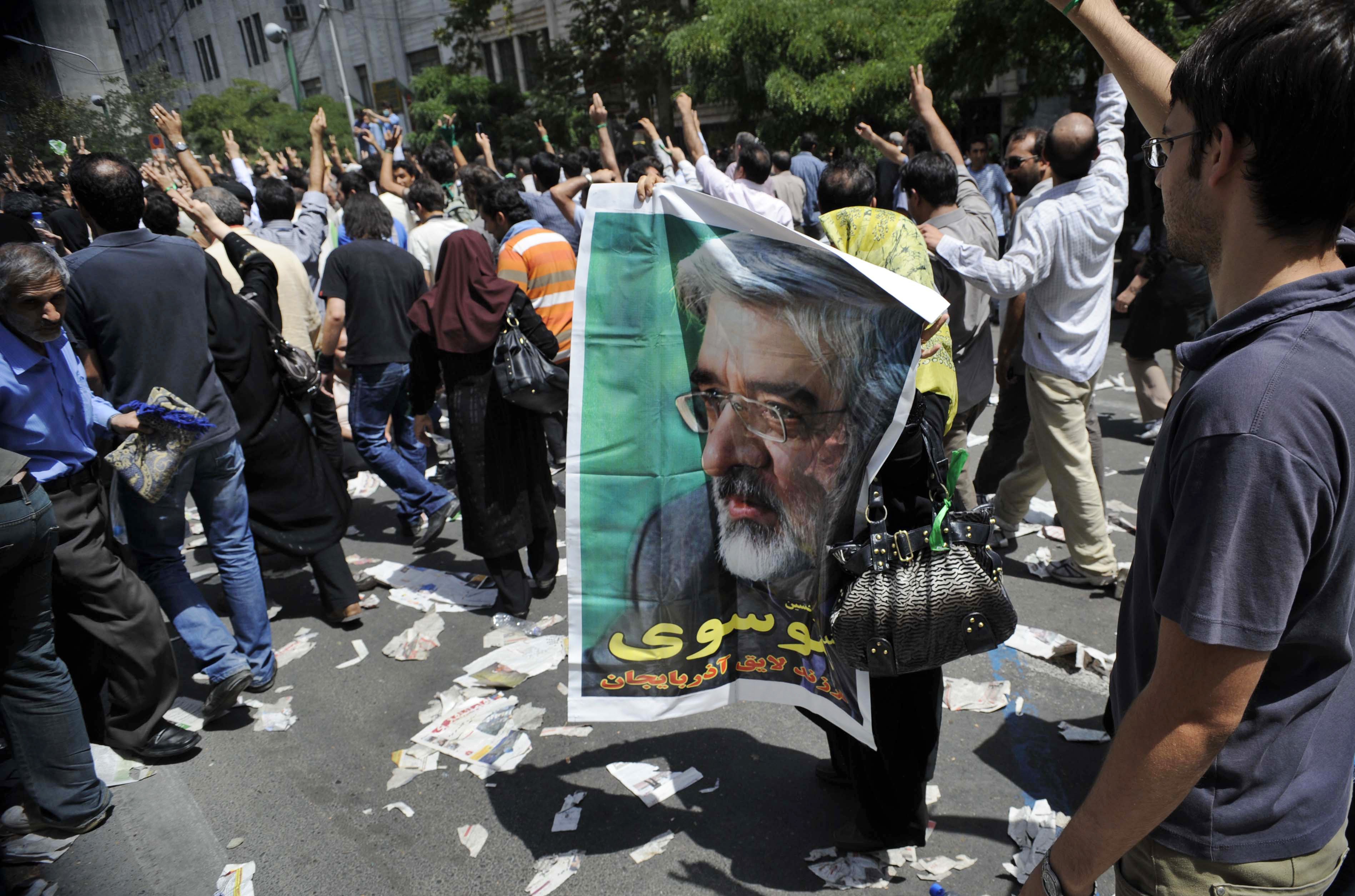 En kvinnlig anhängare håller upp en poster av Mousavi.